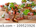 Delicious canapes with rucola-tomato-salad and fried chanterelles 109523926