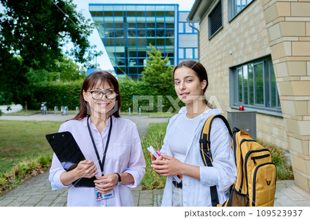 Teenage girl student talking to female teacher, outdoor, school building background Teenage girl student talking to female teacher, outdoor, school building background 109523937