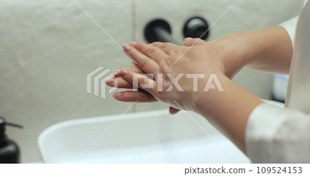 Woman in bathrobe applying moisturizing pampering cream on skin at bathroom. Beauty cosmetics at home. Woman in bathrobe applying moisturizing pampering cream on skin at bathroom. Beauty cosmetics at home. 109524153