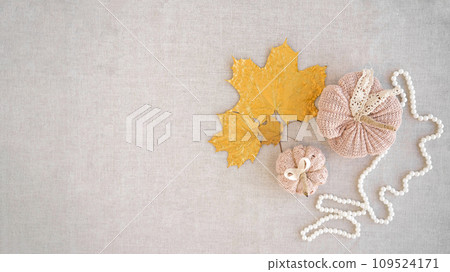 Hobby background with handmade knit pumpkins and golden maple leaves. DIY, craft decoration for fall and winter holidays. Flat lay, top view Hobby background with handmade knit pumpkins and golden maple leaves. DIY, craft decoration for fall and winter holidays. Flat lay, top view 109524171