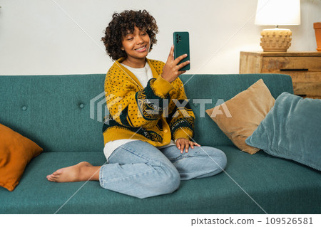 African American girl holding smartphone having video chat. Female blogger chatting with best friends in social network. Young woman having virtual meeting online chat video call at home African American girl holding smartphone having video chat. Female blogger chatting with best friends in social network. Young woman having virtual meeting online chat video call at home 109526581