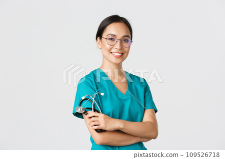 Covid-19, coronavirus disease, healthcare workers concept. Professional good-looking asian doctor, medical worker in glasses and scrubs, cross arms and smiling, white background 109526718