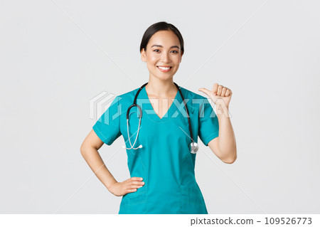Covid-19, healthcare workers, pandemic concept. Professional confident female asian doctor, nurse in scrubs pointing at herself and smiling, guarantee she knows what do, white background 109526773