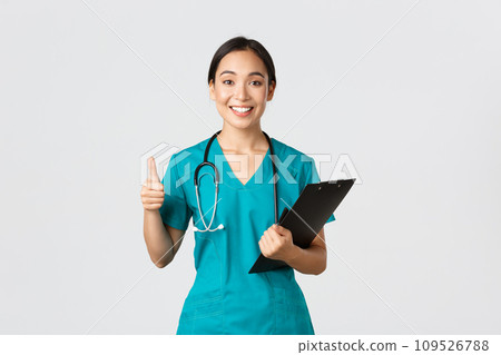 Healthcare workers, preventing virus, quarantine campaign concept. Smiling pretty asian doctor, female intern in scrubs show thumb-up, holding clipboard, bring positive results, white background 109526788