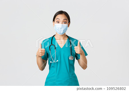 Covid-19, coronavirus disease, healthcare workers concept. Impressed happy asian female doctor, physician in medical mask and scrubs show thumbs-up, agree, compliment choice, praise nice work Covid-19, coronavirus disease, healthcare workers concept. Impressed happy asian female doctor, physician in medical mask and scrubs show thumbs-up, agree, compliment choice, praise nice work 109526802