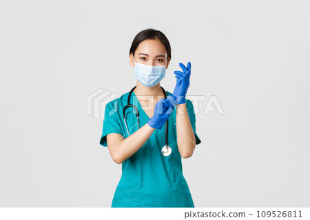 Covid-19, coronavirus disease, healthcare workers concept. Professional and confident smiling asian physician, nurse wear rubber gloves and medical mask for patient examination, white background 109526811