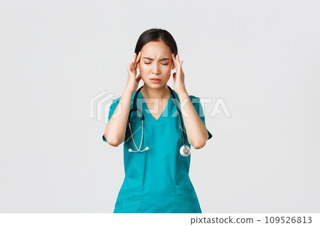 Covid-19, healthcare workers, pandemic concept. Overworked and tired young asian female nurse close eyes, grimacing from headache, feel dizzy, night shift with coronavirus patients, white background 109526813