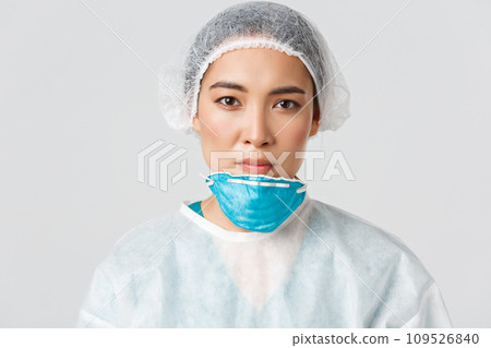 Covid-19, coronavirus disease, healthcare workers concept. Close-up of tired, exhausted asian female doctor take-off respirator and protective glasses, nurse have skin damage after shift at hospital 109526840