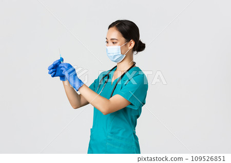 Covid-19, coronavirus disease, healthcare workers concept. Profile of asian female doctor, nurse in medical mask and globes, fill syringe with vaccine, doing vaccination shots, white background 109526851