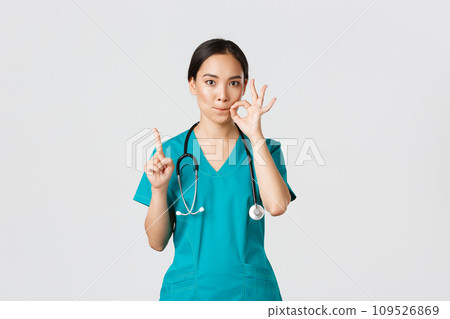 Covid-19, healthcare workers, pandemic concept. Serious-looking worried asian female nurse, physician asking keep secret, shaking finger and showing mouth seal, zipping lips gesture 109526869
