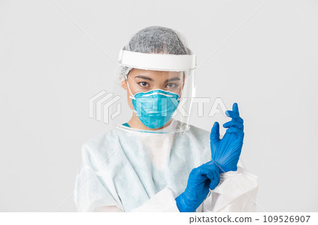 Covid-19, coronavirus disease, healthcare workers concept. Close-up of confident, professional female doctor put on personal protective equipment and rubber gloves to examine patient 109526907