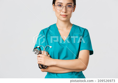 Covid-19, coronavirus disease, healthcare workers concept. Confident smiling professional asian doctor in glasses, cross arms chest, wearing scrubs and holding stethoscope, white background 109526973