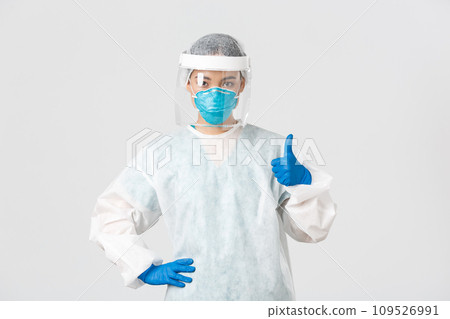 Covid-19, coronavirus disease, healthcare workers concept. Serious-looking professional female asian doctor in personal protective equipment, showing thumb-up, ensure safety of patient 109526991