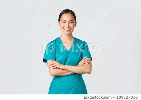 Covid-19, healthcare workers, pandemic concept. Confident smiling asian doctor, female nurse in scrubs standing determined, cross arms chest over white background. Doctor ready for shift in clinic 109527010