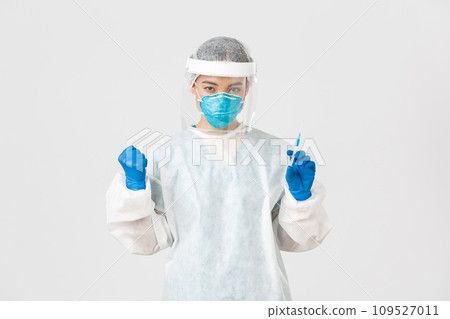 Covid-19, coronavirus disease, healthcare workers concept. Determined and confident female asian doctor, tech lab employee in personal protective equipment holding syringe with vaccine 109527011