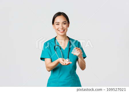 Healthcare workers, preventing virus, quarantine campaign concept. Smiling friendly asian female doctor, physician in scrubs, give patient medication from container, white background Healthcare workers, preventing virus, quarantine campaign concept. Smiling friendly asian female doctor, physician in scrubs, give patient medication from container, white background 109527021
