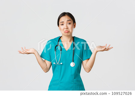Covid-19, healthcare workers, pandemic concept. Portrait of clueless asian female nurse, woman doctor shrugging and spread hands sideways unaware, dont know, cant help, white background 109527026