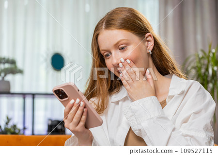 Happy young girl at home use smartphone typing browsing wow yes found out great big win celebrate Happy young girl at home use smartphone typing browsing wow yes found out great big win celebrate 109527115