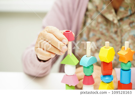 Asian elderly woman playing puzzles game for treatment dementia prevention and Alzheimer disease. 109528163