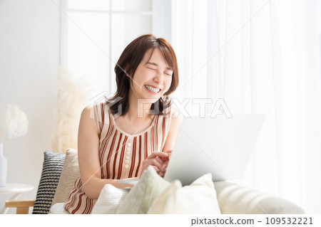 A woman watching a laptop computer in the room 109532221