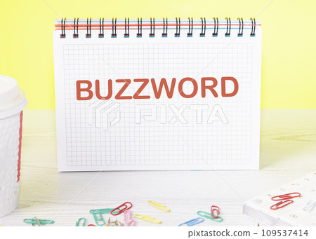 Buzzword the word is written on a blank sheet in a notebook standing on a table on a yellow background 109537414