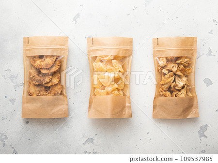 Packages with dried sweet pineapple slices and chips on light background. 109537985