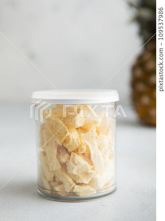 Plastic jar of freeze dried pineapple slices on light table.Macro Plastic jar of freeze dried pineapple slices on light table.Macro 109537986