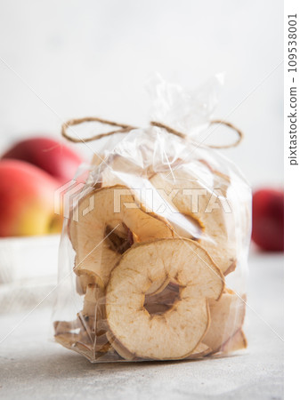 Organic dried apple rings in clear package and red ripe apples in box. 109538001