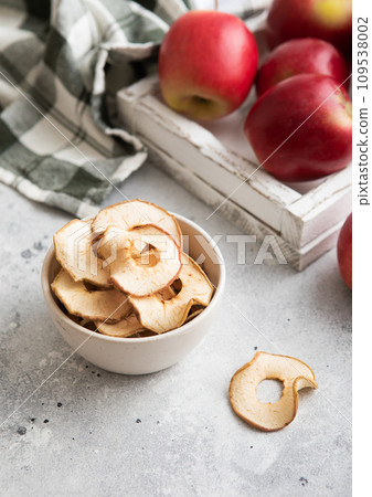 Bowl with dried apple rings with red ripe apples in box. 109538002