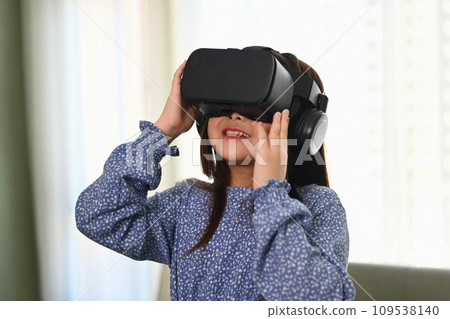 Happy schoolgirl using VR glasses for education learning. Future education technology concept. 109538140