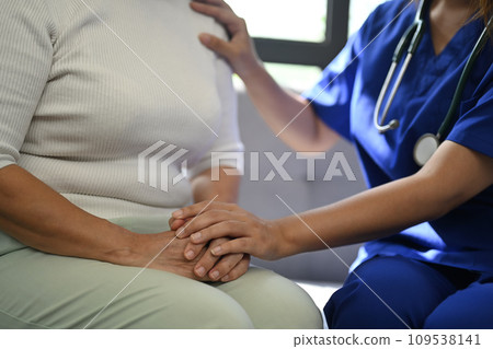 Cropped shot of doctor holding hands of senior patient for giving support, empathy and understanding. 109538141