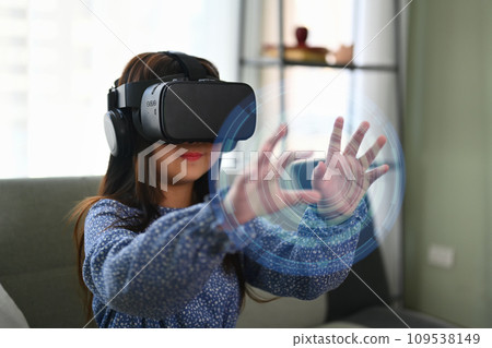Amazed girl experiencing via VR headset and interacting with virtual reality interfaces. Amazed girl experiencing via VR headset and interacting with virtual reality interfaces. 109538149