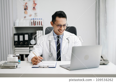 Physician doctor sit on table in hospital. Attractive therapist male practitioner pharmacist smile and use tablet and laptop. after success work from treatment Physician doctor sit on table in hospital. Attractive therapist male practitioner pharmacist smile and use tablet and laptop. after success work from treatment 109538262