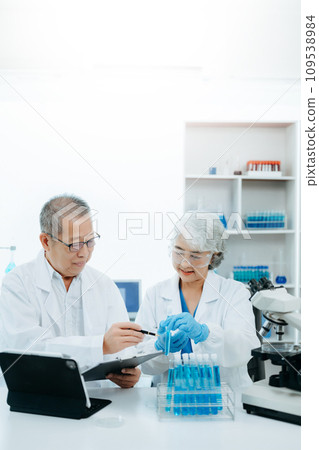 Two scientist or medical technician working, having a medical discuss meeting with Asian senior female scientist supervisor in the laboratory with online reading, test samples and innovation 109538984