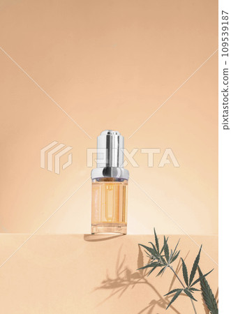glass bottle with CBD oil, THC tincture on a pastel background with cannabis leaves shadows. Pink background 109539187