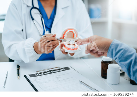 Concentrated dentist sitting at table with jaw samples tooth model and working with tablet and laptop in dental office professional dental clinic. medical doctor working . Concentrated dentist sitting at table with jaw samples tooth model and working with tablet and laptop in dental office professional dental clinic. medical doctor working . 109539274