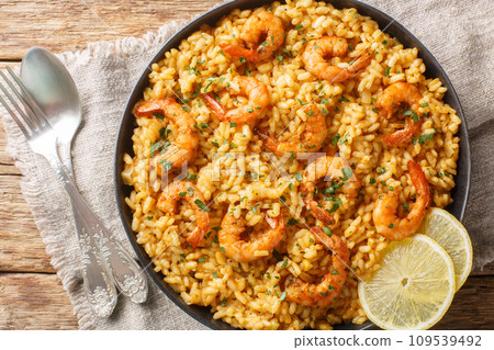 Creamy risotto with shrimps fried prawns, parmesan cheese, lemon and fresh herbs closeup on the plate. Horizontal top view Creamy risotto with shrimps fried prawns, parmesan cheese, lemon and fresh herbs closeup on the plate. Horizontal top view 109539492