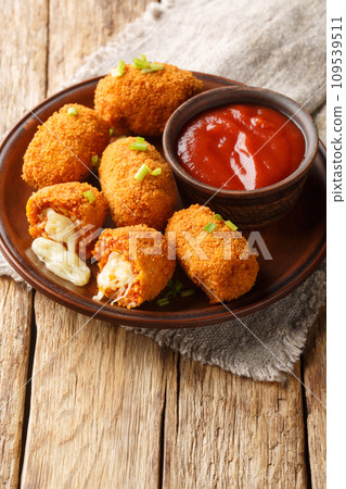 Fried rice balls stuffed with mozzarella suppli al telefono closeup on the plate. Vertical 109539511