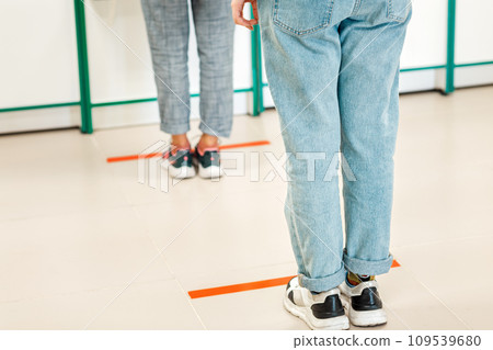People stand in line, legs close-up. Attention line on the floor of the store to maintain social distance. Concept of the coronavirus pandemic and prevention measures People stand in line, legs close-up. Attention line on the floor of the store to maintain social distance. Concept of the coronavirus pandemic and prevention measures 109539680