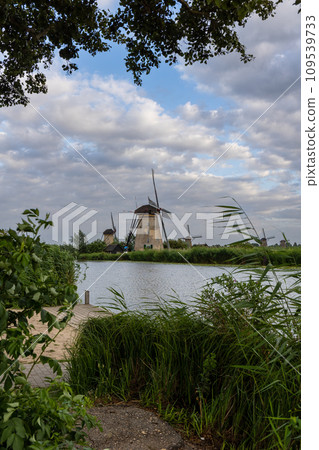 Beautiful wooden windmills at sunset in the Dutch village of Kinderdijk. Windmills run on the wind. The beautiful Dutch canals are filled with water. Beautiful sunset. Beautiful wooden windmills at sunset in the Dutch village of Kinderdijk. Windmills run on the wind. The beautiful Dutch canals are filled with water. Beautiful sunset. 109539733