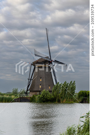 Beautiful wooden windmills at sunset in the Dutch village of Kinderdijk. Windmills run on the wind. The beautiful Dutch canals are filled with water. Beautiful sunset. Beautiful wooden windmills at sunset in the Dutch village of Kinderdijk. Windmills run on the wind. The beautiful Dutch canals are filled with water. Beautiful sunset. 109539734
