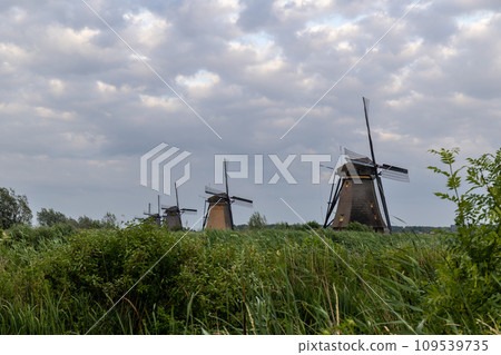 Beautiful wooden windmills at sunset in the Dutch village of Kinderdijk. Windmills run on the wind. The beautiful Dutch canals are filled with water. Beautiful sunset. Beautiful wooden windmills at sunset in the Dutch village of Kinderdijk. Windmills run on the wind. The beautiful Dutch canals are filled with water. Beautiful sunset. 109539735