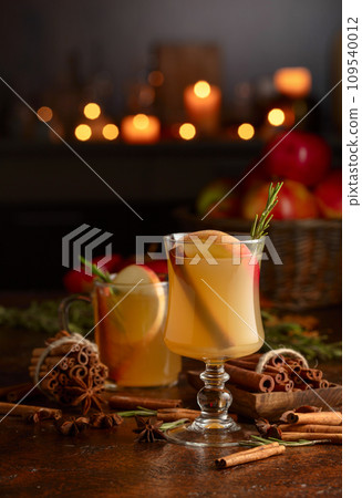 Mulled cider with apples, cinnamon, rosemary, and anise on a background of burning candles. 109540012