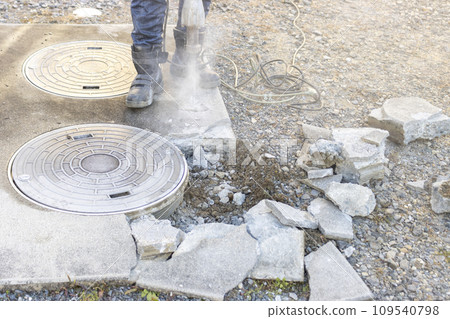 A worker breaking the concrete of a septic tank 109540798