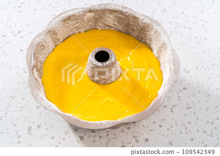 Pouring cake batter into a greased bunt cake pan to bake a simple vanilla bundt cake. Pouring cake batter into a greased bunt cake pan to bake a simple vanilla bundt cake. 109542349