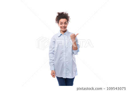 young fashion woman caucasian woman with curly black hair gathered in a ponytail wears a blue shirt 109543075