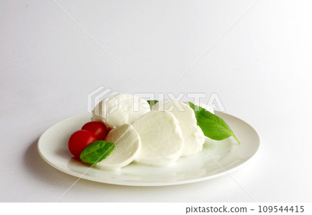 Mozzarella cheese, red tomatoes, and green basil on a white plate Mozzarella cheese, red tomatoes, and green basil on a white plate 109544415