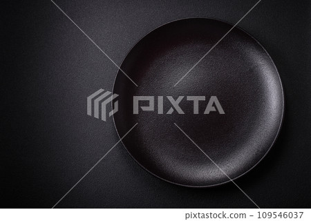 Bumpy empty ceramic plate on a textured concrete background Bumpy empty ceramic plate on a textured concrete background 109546037