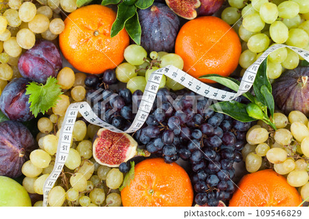 Diet concept with measuring tape, orange tangerine, figs and grape fruit mix with green leaves. Diet concept with measuring tape, orange tangerine, figs and grape fruit mix with green leaves. 109546829