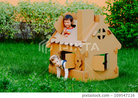 Children are playing in cardboard kid house. Child having fun outdoors. Children are playing in cardboard kid house. Child having fun outdoors. 109547116